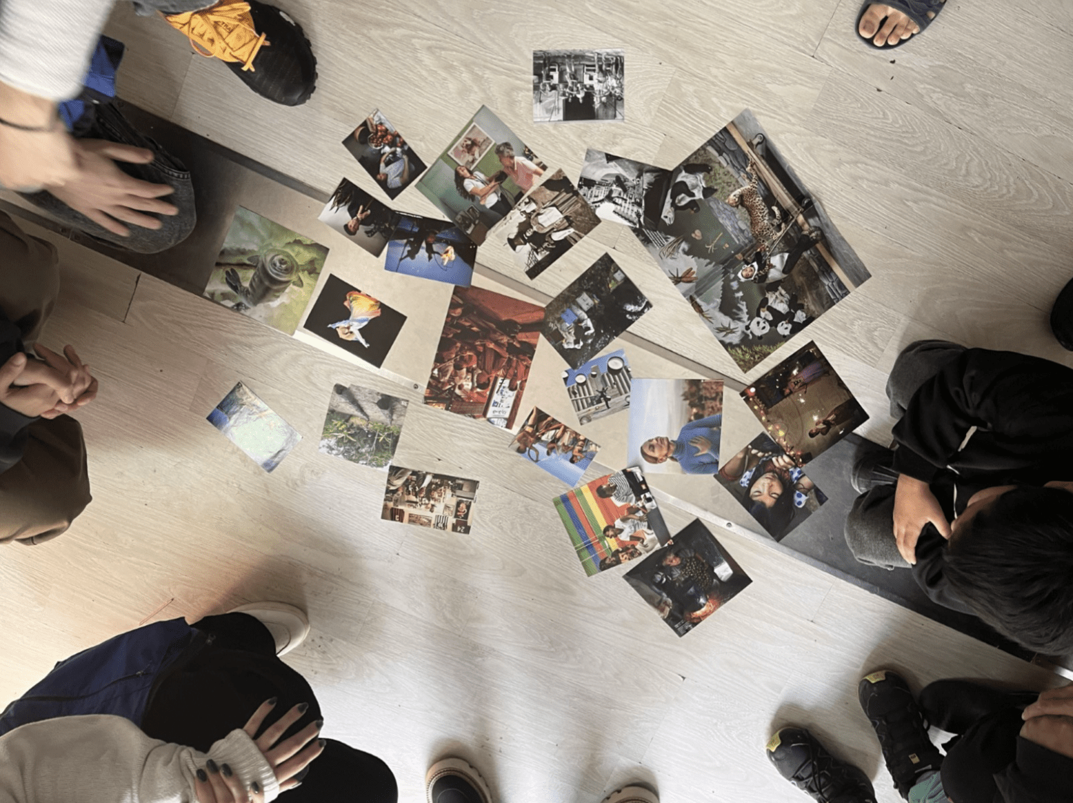 Printed photos spread out on the ground and participants sitting in a circle around them